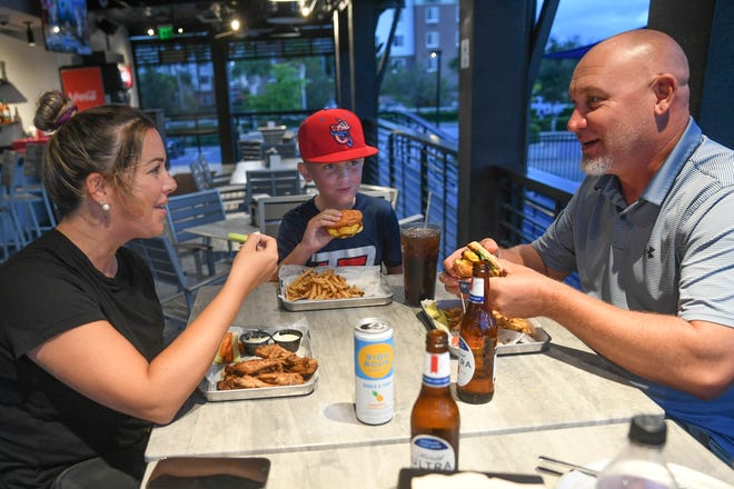 Lauren and Jason Stelmacki of Port St. Lucie dine with their son Jordan, 10, next to the full bar overlooking the putting courses at the newly renovated PopStroke on Monday, Oct. 10, 2022.