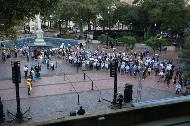 Community members gather as UNF President Moez Limayem speaks at the lectern during a vigil organized by OneJax following a spate of hate speech.
