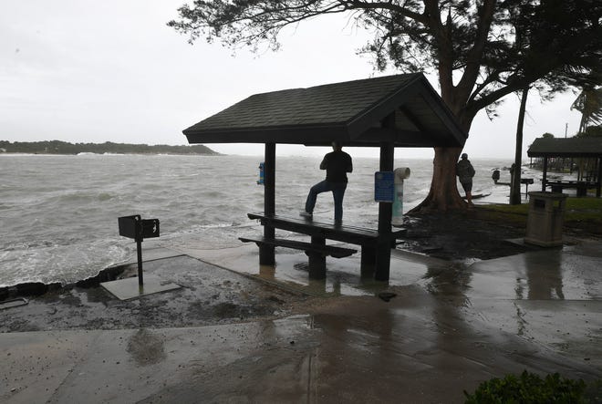 Chris Finno (center), of Vero Beach watches the waves ahead of Tropical Storm Nicole as they spill over the inlet stones and onto the sidewalk along the shoreline of Jetty Park on Wednesday, Nov. 9, 2022, in Fort Pierce. "It's wild, I love it, I love storms," Finno said. "I love just watching the power of them."