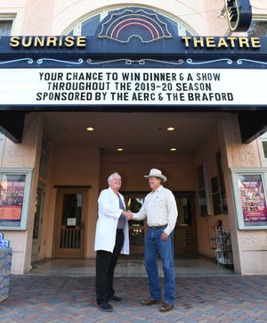 Dr. Ron Lyman, left, and Mike Adams in front of the Sunrise Theatre marquee promoting the chance to win dinner and show tickets.