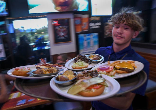 Food runner Caden Krause sprints from the kitchen with burgers for customers during burger night in the St. Lucie Draft House on Wednesday, Aug. 31, 2022, in Port St. Lucie. "The whole family works here, it's kind of a family reunion thing, it's a great place to work," Krause said.