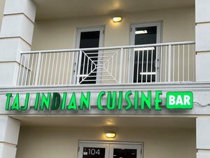 Taj Indian Restaurant and Bar is on the first floor of a modern multi-use building.