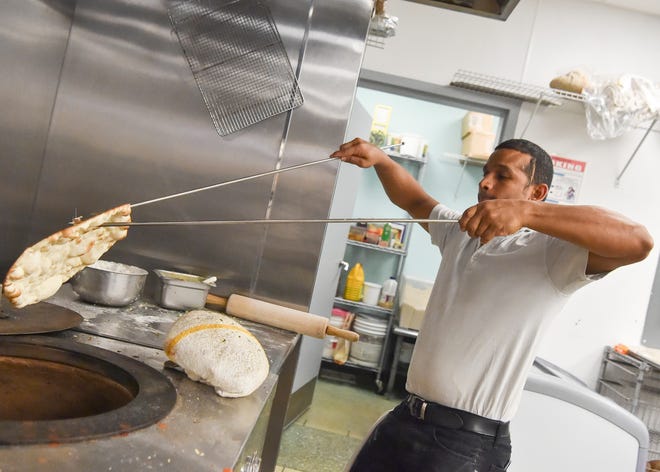 Savio Dessai pulls cooked naan from a tandoor oven during dinner service on Saturday, Oct. 30, 2021, at Bolly Twist in Martin County. Owner Manjit Kaur, born in Punjab, India, opened the Martin County restaurant in the Treasure Coast Square food court in February 2020, then moved to Salerno Village Square Plaza the next year.