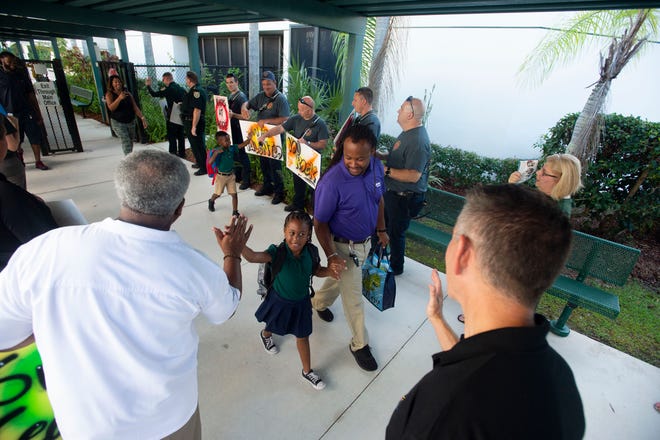 Rivers Edge Elementary School first grader Aaliyah Joseph, 6, and her father David Joseph, of Port St. Lucie, is greeted by Kids at Hope project coordinator Kevin Singletary on the first day of school, Monday, Aug. 12, 2019. School students and their families were greeted with words of encouragement by members and staff of St. Lucie Public Schools, the Children's Services Council, St. Lucie Fire Rescue and the St. Lucie County Sheriff's Office at the Kids at Hope sponsored tunnel of hope. "I'm excited. This is going to be a great year. It's really nice to have the kids back on campus," said principal Jennifer Ingersoll. "They're pretty awesome," she said of the 650 students who attend Voluntary Pre-kindergarten through fifth grade at the school.
