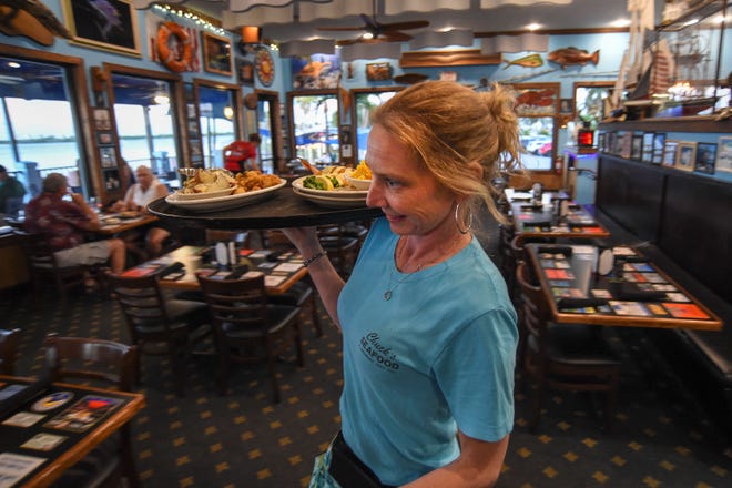 Brooke Hammond, a server at Chuck's Seafood Restaurant, carries dinners from the kitchen to her customers while working on Tuesday, Nov. 29, 2022, in Fort Pierce. Workers at restaurants, hotels, and other tourism venues have had challenges finding affordable housing.  "I had to find some place to rent. I had to go to an area I didn't want to, to be able to afford it," Hammond said.