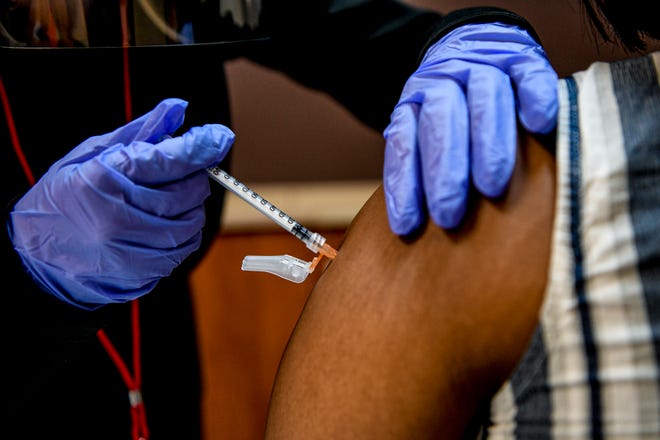 A health care worker administers a COVID-19 vaccine in Washington in 2021 during last winter's COVID surge.