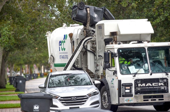 FCC Environmental Services driver Maxo Celidor collects curbside trash around a vehicle parked along Montserrat Place in the VillageWalk neighborhood on Monday, August 29, 2022, in Wellington. FCC will not pick up trash placed in piles curbside on their normal routes.