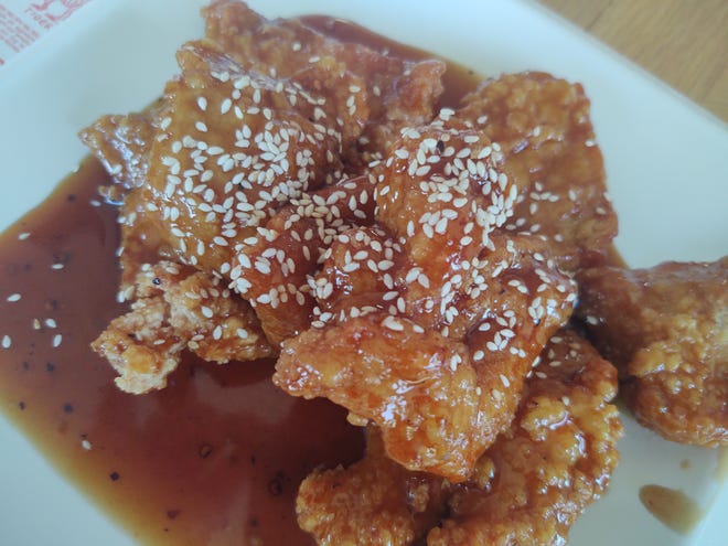 Sesame chicken at Red Wok is battered and crispy fried with a thick sauce featuring sesame seeds and oil.