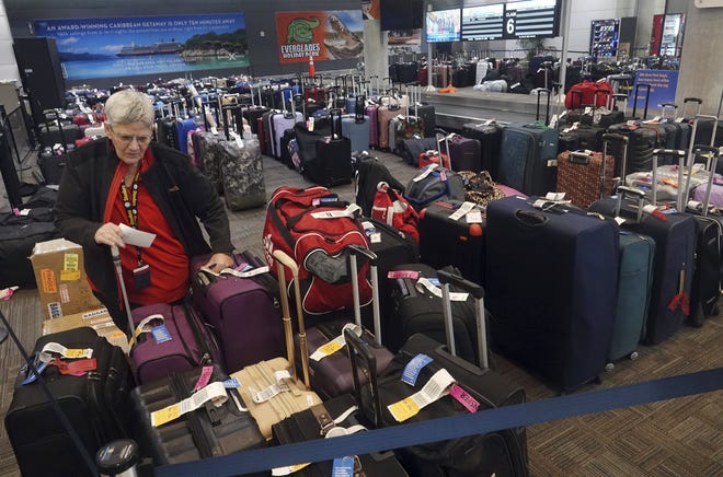 An employee of Southwest Airlines checks unclaimed and rerouted luggage, Tuesday, Dec. 27, 2022, at Fort Lauderdale-Hollywood International Airport, in Fort Lauderdale. A brutal winter storm has caused major delays in air travel across the U.S.
