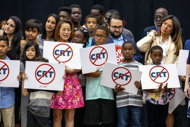Kids holding signs against Critical Race Theory stand on stage near Florida Gov. Ron DeSantis as he addresses the crowd before publicly signing HB7, "individual freedom," also dubbed the "stop woke" bill during a news conference at Mater Academy Charter Middle/High School in Hialeah Gardens, Fla., on Friday, April 22, 2022. DeSantis also signed two other bills into laws including one regarding the "big tech" bill signed last year but set aside due to a court ruling, and the special districts bill, which relates to the Reedy Creek Improvement District.