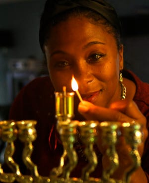 Yael Respes Farr, at home in West Melbourne, demonstrating the lighting of the Menorah.
(Photo: TIM SHORTT/ FLORIDA TODAY)