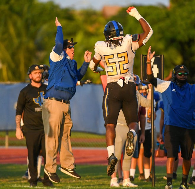 John Carroll defensive end Wilky Denaud (52) celebrates a fourth down stop with a defensive coach during the first quarter against Cardinal Newmanin West Palm Beach.