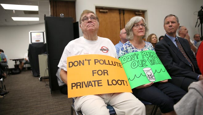 Husband and wife Don and Nancy Crane hold signs in protest of water quality standard changes during a meeting with the Environmental Regulation Commission at the DEP building on Tuesday.