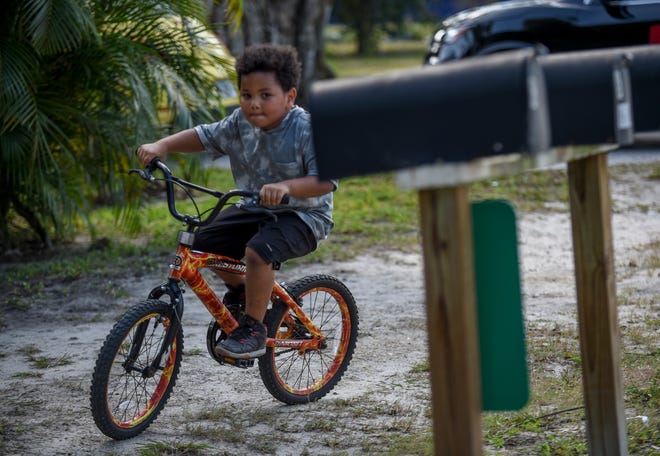 Carter Lynch rides around the street of his family's new rental home on Monday, Dec. 5, 2022, in the Banner Lake neighborhood in Hobe Sound. Carter's mom Michelle Chartoff was worried about being able to provide some toys for her son for Christmas until discovering the Toys for Tots and United Way Holiday Project.
