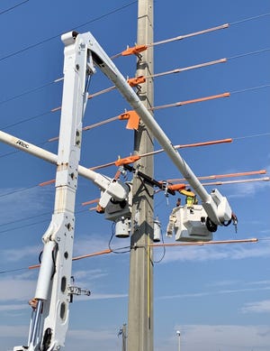 Workers use protective sleeves on poles as a safety measure when making repairs on power lines in Lake Worth Beach.