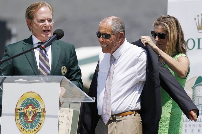 Monica Seles, right, helps Nick Bollettieri with a blazer as Hall of Fame chairman of the board Christopher Clouser, left, looks on during Bollettieri's 2014 induction into the International Tennis Hall of Fame. Bollettieri died Sunday.