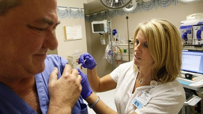 Registered nurse Leah Serio, clinical manager of the emergency department at Boca Raton Regional Hospital, gives a flu shot to Dr. Jack Kareff in September.