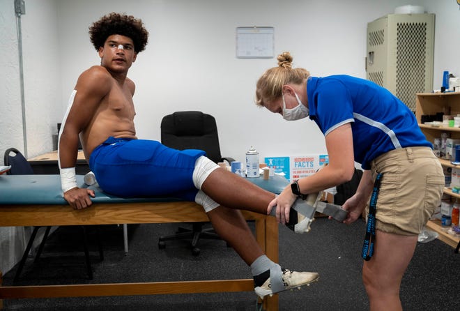 Cardinal Newman's Tovani Mizzell gets his ankle taped by athletic trainer Abbe Kisrow before their game against    King's Academy in West Palm Beach, Florida on August 27, 2021.