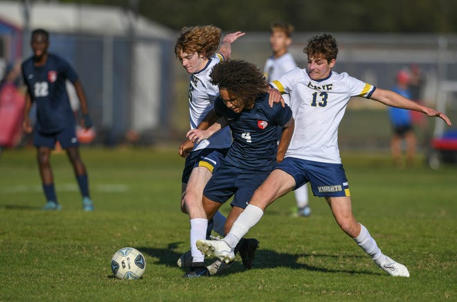 Aerian Hammond (center) of St. Lucie West Centennial,  along with Christian Kerr (left) and Henry Alexandrescu of the Pine School, race for control during the first half of their boys soccer match at St. Lucie West Centennial High School on Wednesday, Jan. 11, 2023, in Port St. Lucie. The game ended in a draw 1-1.