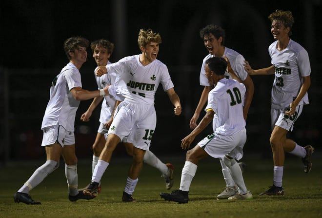 Dylan Bruns (15), of Jupiter High School (center), celebrates with his teammates after scoring the first goal past St. Lucie West Centennial during the first half of their Boys District 10-7A match at the South County Stadium on Thursday, Feb. 2, 2023, in Port St. Lucie. Jupiter won 2-1.