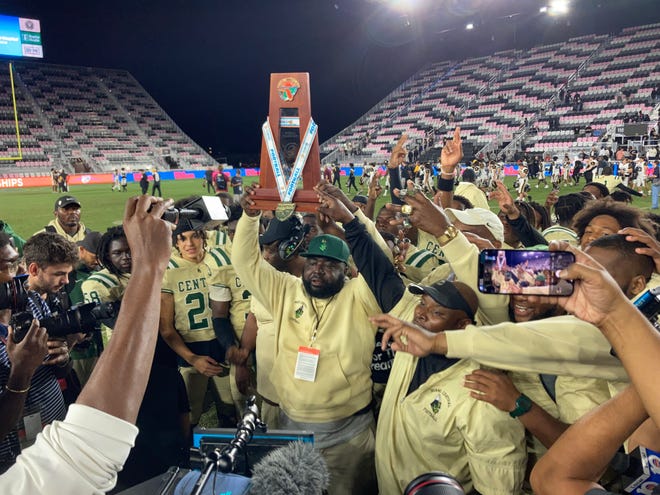 Miami Central coach Jube Joseph lifts the Class 2M state championship after the Rockets 38-31 win against American Heritage on Dec. 16 at DRV PNK Stadium in Fort Lauderdale.