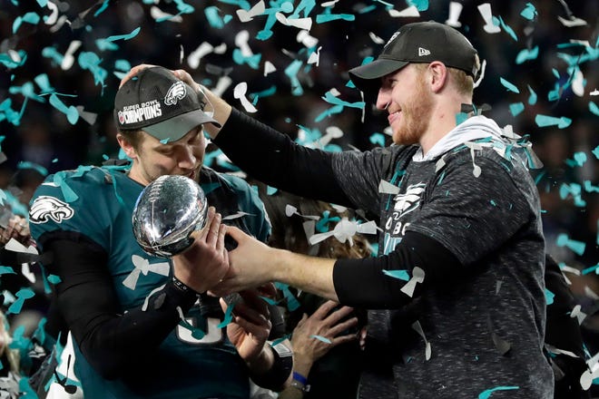 In this Feb. 4, 2018, file photo, Philadelphia Eagles quarterback Carson Wentz, right, hands the Vincent Lombardi trophy to Nick Foles after the Eagles defeated the New England Patriots 41-33 in the NFL Super Bowl 52 football game in Minneapolis.