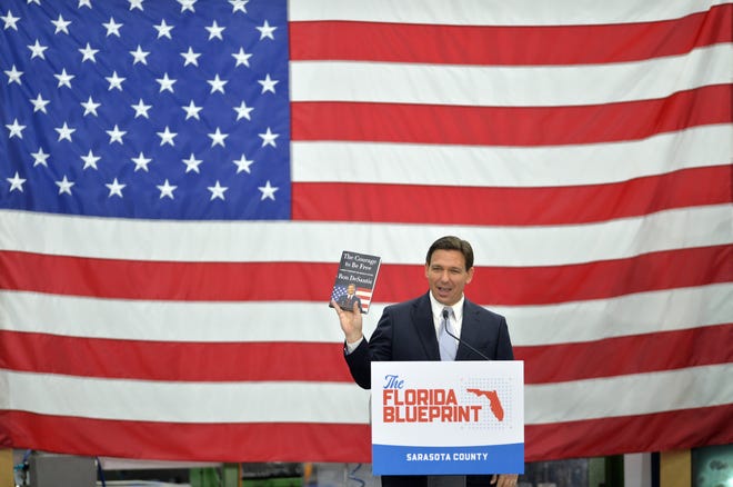 Florida Governor Ron DeSantis holds up a copy of his new book "The Courage to be Free" during an campaign-style event Tuesday morning at PGT Innovations in Venice.