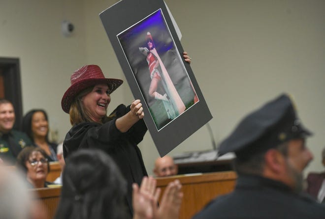 Judge Nicole Menz waves a photo of Leatha Mullins around the courtroom during a comedy presentation of Mullins before her swearing in during the Investiture Ceremony for Mullins at the St. Lucie County Courthouse on Friday, Feb.24, 2023, in Fort Pierce.