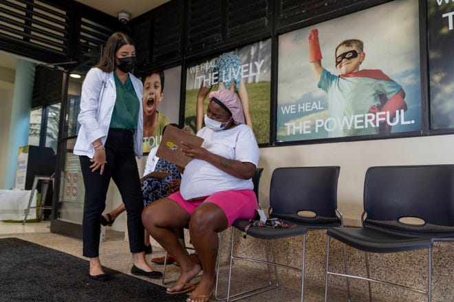 Stephanie Trujillo Rodriguez helps Jackie Edwards who is expecting twins to register for her first shot of the Pfizer COVID-19 vaccine at "Play date to vaccinate" at Palm Beach Children's Hospital at St. Mary's Medical Center in West Palm Beach, in this photo from August 31, 2021.