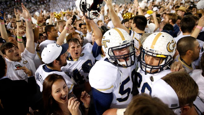 Georgia Tech fans storm the field and surround their team after they returned a blocked field goal for the win as time expired against FSU at Bobby Dodd Stadium on Saturday, Oct. 24, 2015.