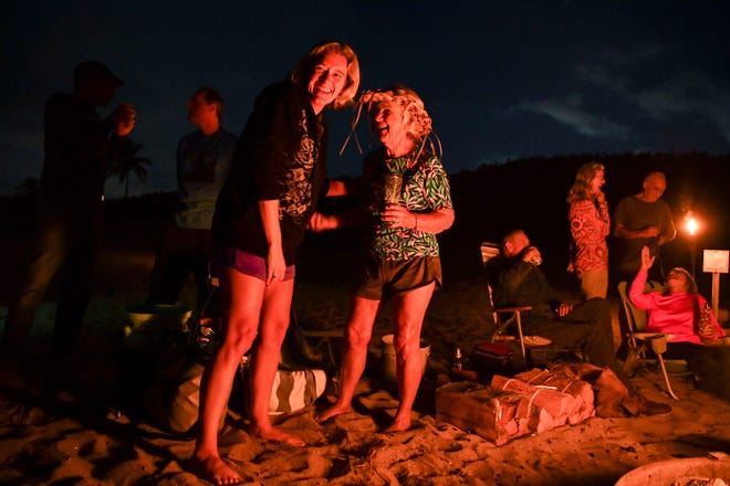 Ellie Golden (left), laughs with Nicki Campbell, 81, both of Stuart, during a full moon bonfire, Thursday, Dec. 5, 2023, at Stuart Beach. Campbell organized the event for all her surfing and beach friends. "Nicki is just an amazing woman," said Golden. "She's a role model and very kind and supportive. She's excited about life and shares that with other people. She cares about people. She's fun to be around and she's a true friend."