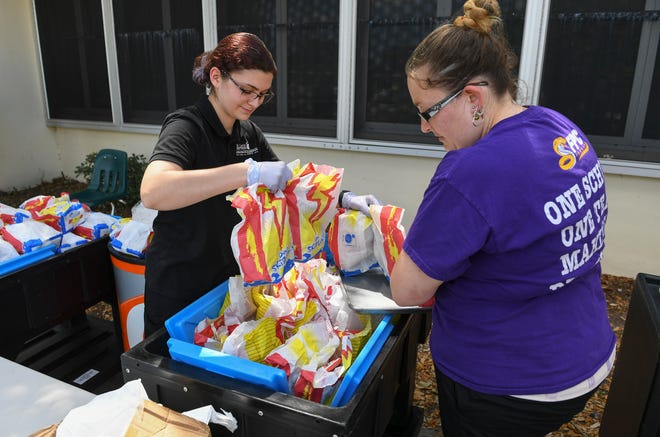 St. Lucie Public Schools staff help out assembling and distributing "Grab and Go" meals for school children at the C.A. Moore Elementary School bus loop on Monday, March 30, 2020, in Fort Pierce. The St. Lucie Public Schools Child Nutrition Services Department is serving the meals, including breakfast lunch, and dinner, with reheating instructions, for students in our community from 11:00 am to 1:00 pm, Monday through Friday, at participating schools during the COVID-19 pandemic. School staff will be on-site to pack and distribute the meals from the bus loops while following social distancing guidelines. Go go https://www.stlucie.k12.fl.us/ for the list of schools and more information on the program.
