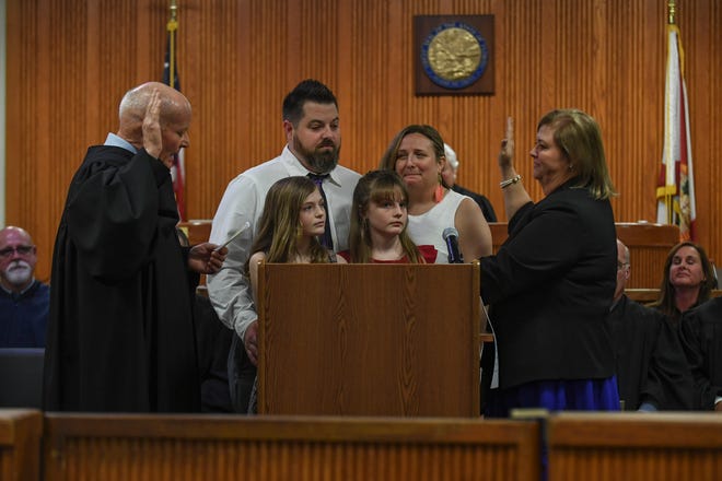 Judge Burton Connor (left) performs administration of the oath to Leatha Mullins (right), as her family watches, during the Investiture Ceremony for Mullins at the St. Lucie County Courthouse on Friday, Feb.24, 2023, in Fort Pierce.