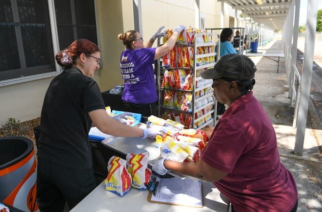 Janice Ferschke (left), staff at Samuel Gaines Academy K-8 School, and Beverly Williams (right), staff at Fort Pierce Westwood High School, help out assembling "Grab and Go" meals for school children at the C.A. Moore Elementary School bus loop on Monday, March 30, 2020, in Fort Pierce. "It feels great, it's an awesome thing for us to do for the community," Williams said.