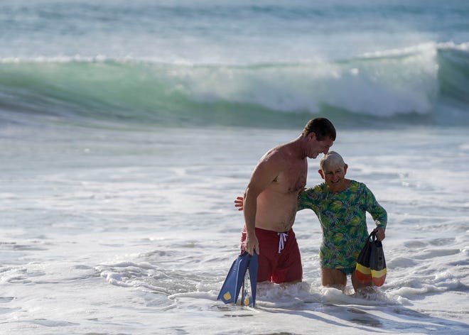 Nicki Campbell (right), 81, of Stuart, and Mike Mammen, a lifeguard with Martin County Ocean Rescue, head to the beach after body surfing together during a Surfers for Autism event, Saturday, Sept. 10, 2022, at Jensen Beach Park. After her husband George Arthur "Art" died in 2015, Campbell met Mammen and other lifeguards while walking and eventually jogging the beaches in Martin County. "I owe them a tremendous thank you," said Campbell. "Twice I went with Mike and the Martin lifeguard team and competed in the annual Vero Beach Lifeguard Bodysurfing competition. I made the finals thanks to his coaching and they awarded me 'Wave of the Day.' "