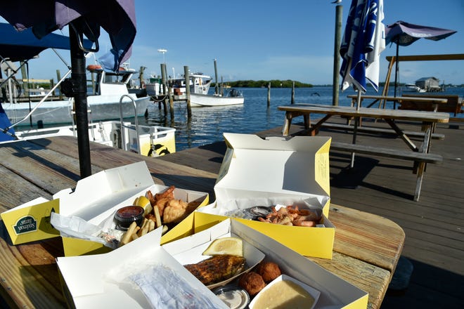 Clockwise from front: blackened grouper, conch fritters and cheese grits; mahi mahi, fried shrimp, lemon, cocktail sauce, conch fritters, French fries and coleslaw; and peel and eat shrimp at Star Fish Company in Cortez.