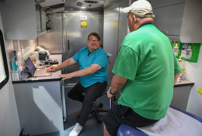 Dr. Joe Holbrook (left) consults with his patient Richard Champion, inside the HANDS Clinic mobile healthcare van while parked outside the St. Lucie County Housing Hub, a homeless shelter on North 7th Street, on Thursday, March 16, 2023, in Fort Pierce. The HANDS Clinic of St. Lucie County is able to take health care on the road to reach residents like Champion, an uninsured resident in Fort Pierce, to provide health care services for those in need.