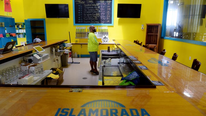 Jose Herrera, co-founder of Islamorada Beer Company, cleans up behind the bar in the tasting room at the brewery's new building at 3200 St. Lucie Blvd. near the Treasure Coast International Airport and Business Park on Aug. 11, 2016 in Fort Pierce. The brewery is is providing free drinking water at its tap room from 2 to 8 p.m. Wednesday for victims of Hurricane Irma.