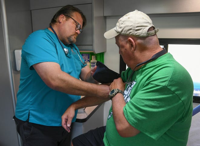 Dr. Joe Holbrook secures a blood pressure collar on patient Richard Champion while inside the HANDS Clinic mobile healthcare van Thursday, March 16, 2023, in Fort Pierce. The HANDS Clinic  launched the heath care vehicle on Feb. 16 to help reach uninsured St. Lucie County residents in need of health care.
