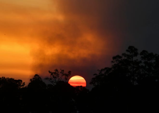 The sun sets as a wildfire burns Thursday evening March 23, 2023, in the John C. and Mariana Jones/Hungryland Wildlife and Environmental Area off Pratt Whitney Road in Martin County near Indiantown.