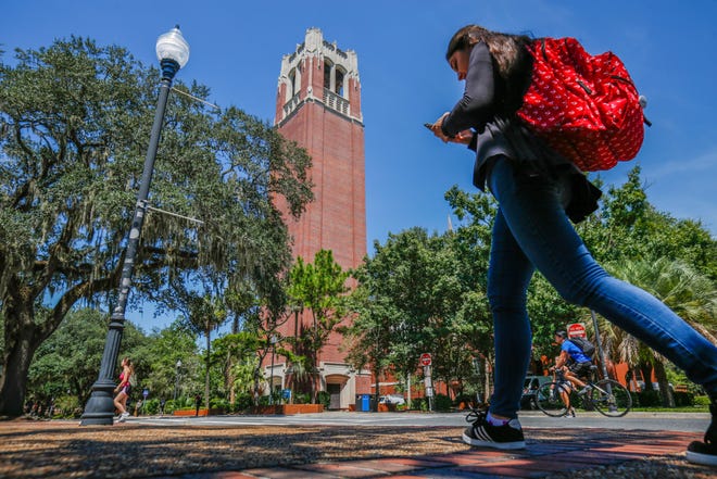 Students walk through the University of Florida campus with Century Tower in the background on August 6, 2019.