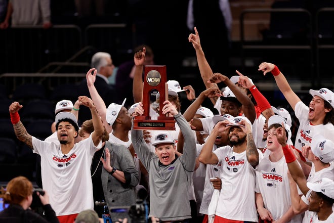 Florida Atlantic head coach Dusty May holds up the trophy as Florida Atlantic players celebrate after defeating Kansas State in the second half of an Elite 8 college basketball game in the NCAA Tournament's East Region final, Saturday, March 25, 2023, in New York. (AP Photo/Adam Hunger)