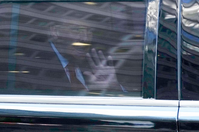 Donald Trump waves from the inside of a vehicle as it turns west onto East 56th St. from Madison Avenue in New York City on Monday.