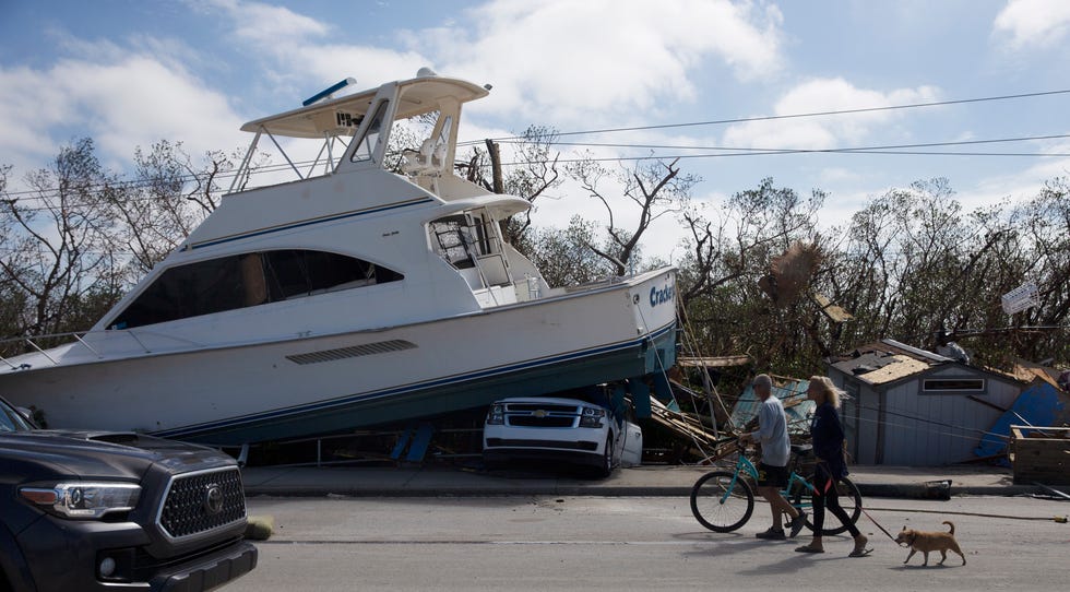 People walk along past damage along San Carlos Boulevard on the way to Fort Myers Beach on Thursday. Hurricane Ian made landfall near the area and devastated the area.