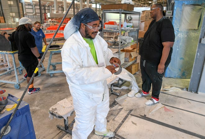 Raheeem Hall (center), a gelcoat tech, suits up in protective clothing to work spraying gelcoat onto a hard top mold for a Maverick sport fishing boat at the Maveric Boat Group on Tuesday, Sept. 20, 2022, in Fort Pierce. "I went back and got my certificate for gelcoat, for boat repair, and now I'm back at boats again," Hall said. Hall was able work after going through the small engine repair program through IRSC Lincoln Park Career Initiatives funded by the Allegany Franciscan Ministries.