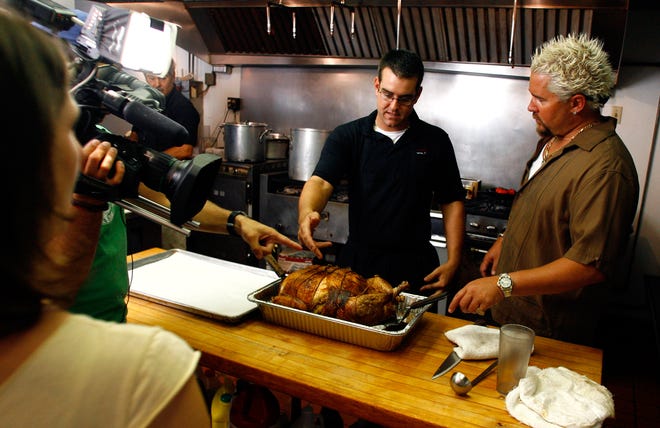 "Diners, Drive-Ins and Dives" host Guy Fieri, right, with The Food Network, chats with Matt Rebhan, son of owner Mark Rebhan, about the Turducken (chicken in a duck in a turkey) he made at the Karl Ehmer's Meats at Alpine Steakhouse in Sarasota, on Wednesday, August 8, 2007.  At left are cameraman Anthony Rodriguez and producer Carly Jacobs.  Crews from The Food Network show were filming for two days at the restaurant, which is somewhat of a local secret, perhaps only until the show airs.