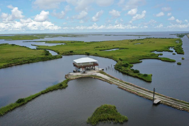 A home on stilts sits amidst coastal waters and marshlands along Louisiana Highway 1 on Aug. 24, 2019, in Grand Isle, Louisiana. National Oceanic and Atmospheric Administration researchers said Louisiana's combination of rising waters and sinking land give it one of the highest rates of relative sea level rise on the planet. A proposed change to Florida's constitution would give homeowners tax breaks for hardening their homes against the effects of rising seas.
