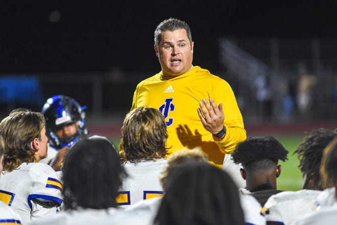 John Carroll head coach Mickey Groody speaks to his team after their 40-7 loss to Cardinal Newman Monday night in West Palm Beach.