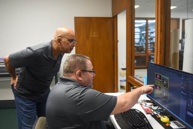 Gus Hernandez, owner of FastSigns, discusses a clients artwork with James Warden, a graphic design and production specialist, before printing at his Port St. Lucie franchise on Monday, Aug. 29, 2022.