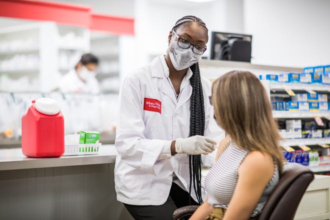In this file photo, a Winn-Dixie pharmacy employee administers the COVID-19 vaccine to a customer. The supermarket chain, operated by Southeastern Grocers, began offering the Moderna vaccine Thursday, Feb. 11, 2021, throughout Florida as part of the Federal Retail Pharmacy Program.